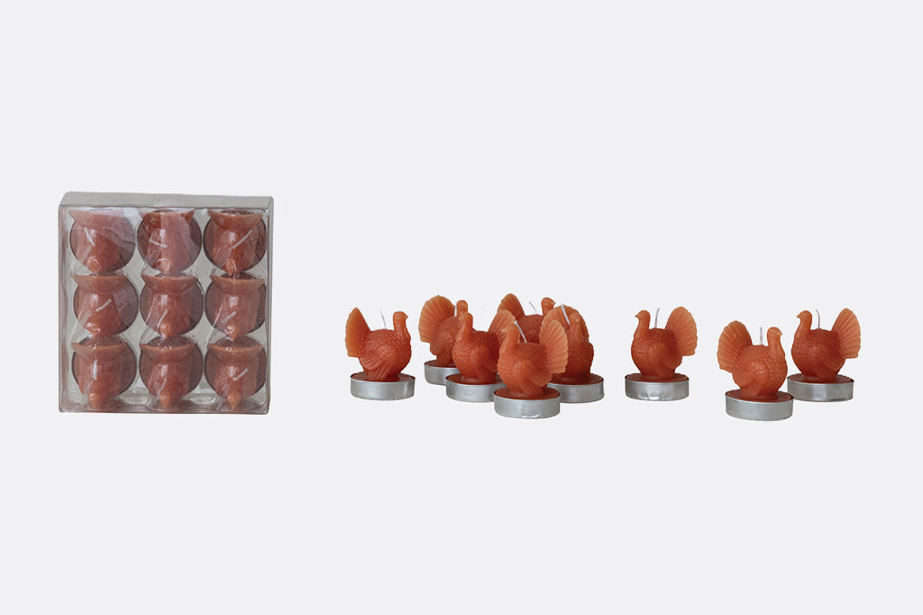 Set of small orange candles with a clear plastic packaging box on a white background