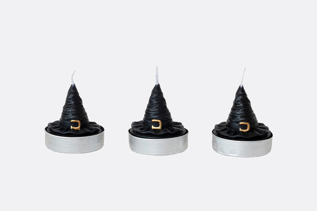 Three black witch hat candles on white background