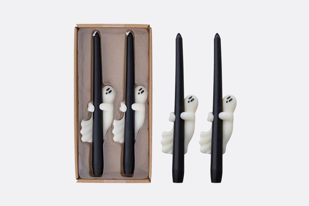 Black candles with ghost decorations in a box on a white background