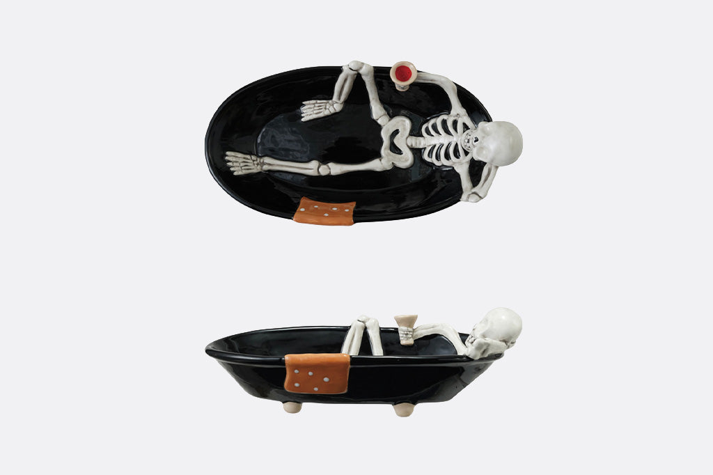 Two black oval trays with skeleton figures on a white background