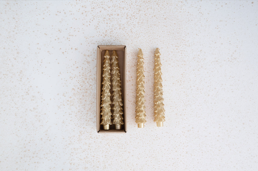 four gold Christmas tree-shaped taper candles, shown with two standing outside a rectangular box and two inside the box