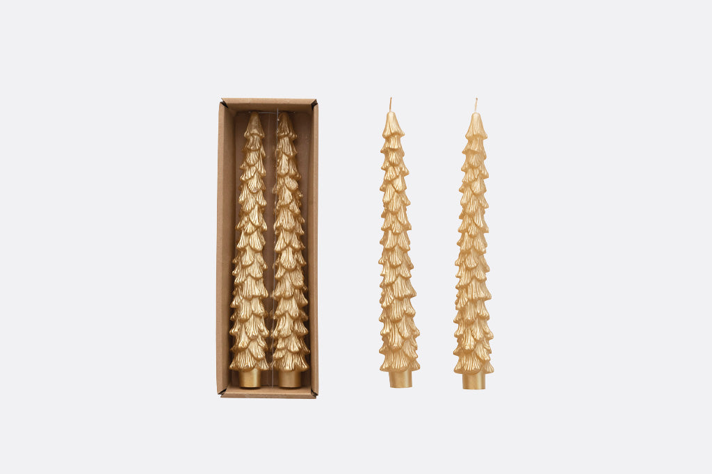 four gold Christmas tree-shaped taper candles, shown with two standing outside a rectangular box and two inside the box on a light gray background.