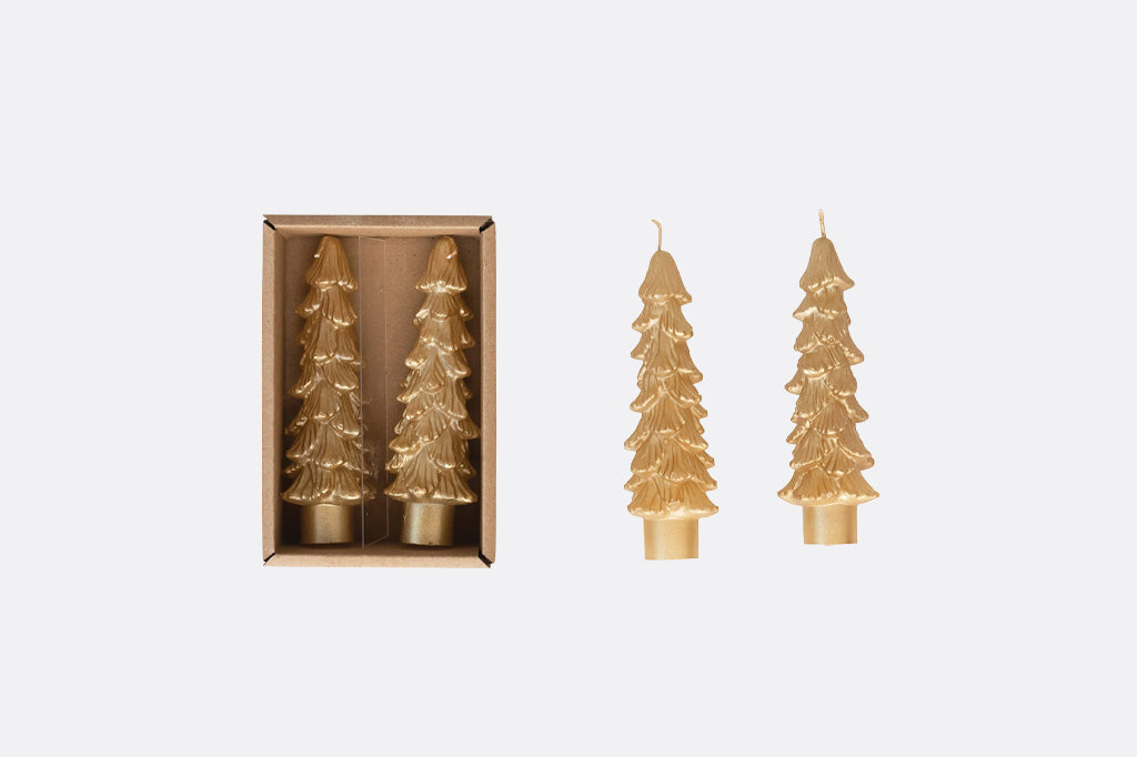 Four gold Christmas tree-shaped candles, with two inside a small brown box and two standing beside it, on a light grey background.
