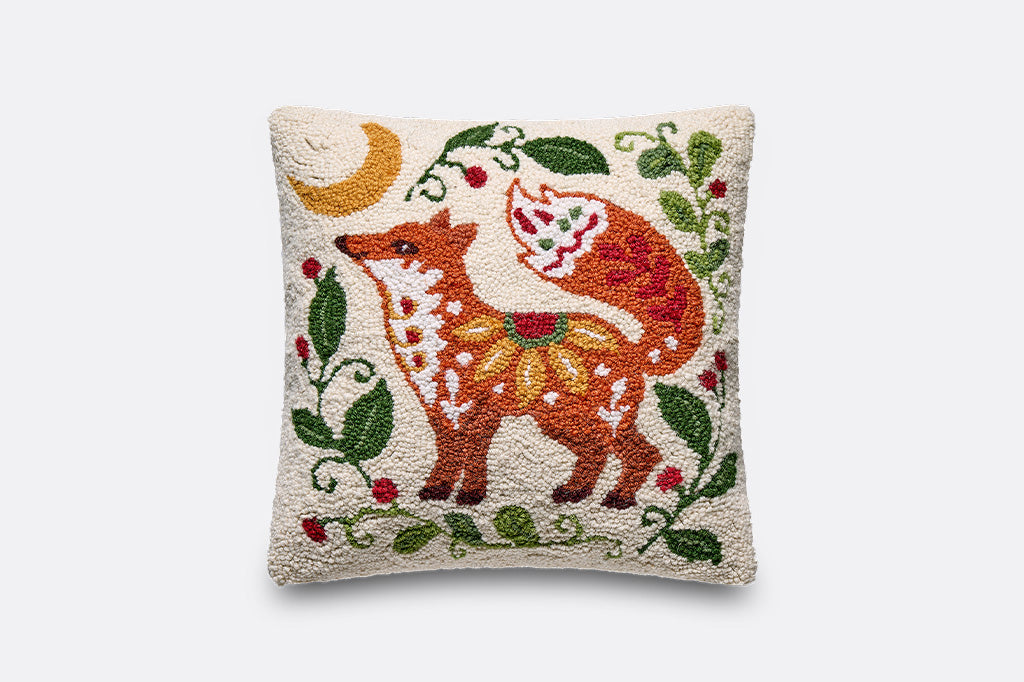 A square decorative throw pillow featuring a colorful embroidered fox, moon, and floral vine pattern on a cream-colored textured fabric background.