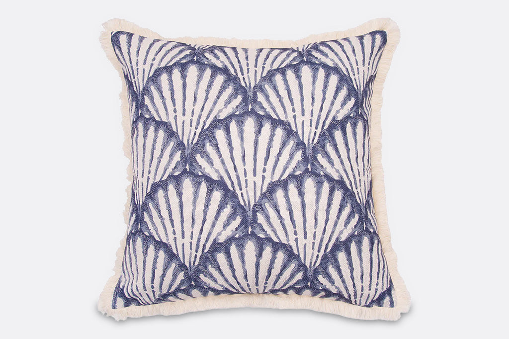 A blue and white seashell patterned embroidered pillow.