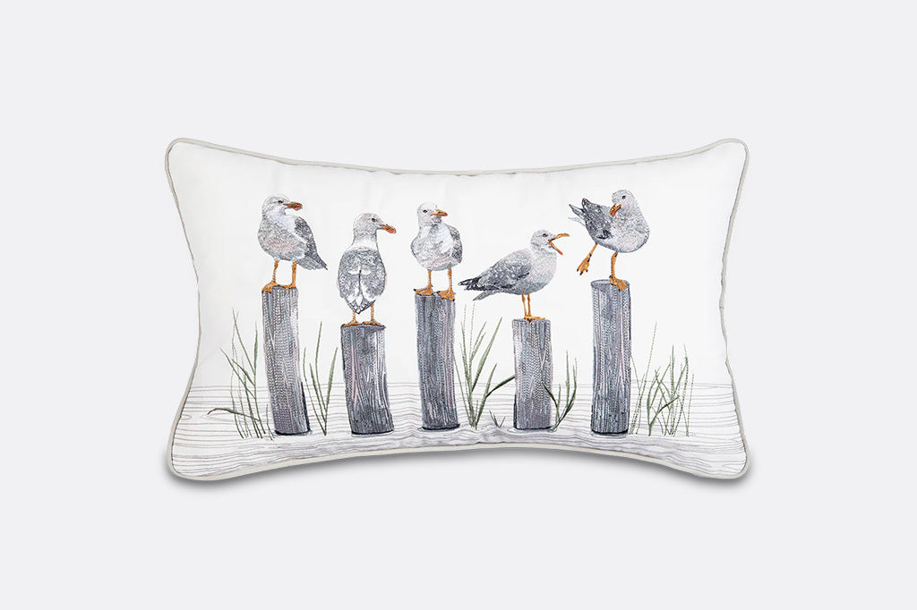 A pillow featuring 5 seagulls standing on poles.
