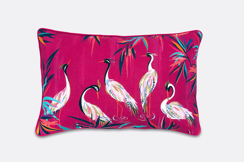 Decorative pillow with colorful bird pattern on a pink background