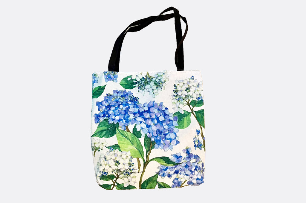 tote bag with garden print of blue hydrangeas. Black handles.