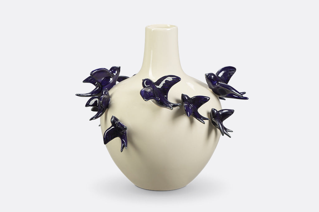 A vase of blue birds flying around.