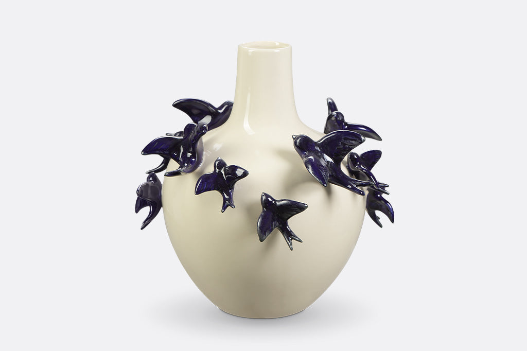 A vase of blue birds flying around.