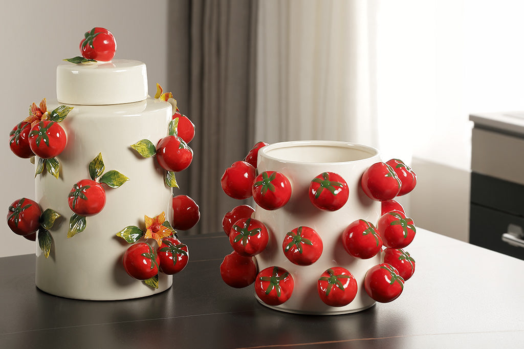 Two decorative vases with tomato designs on a table.