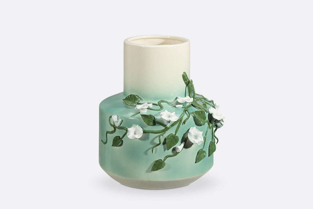 A vase with a green colorway and a design of vines and blossoming flowers.