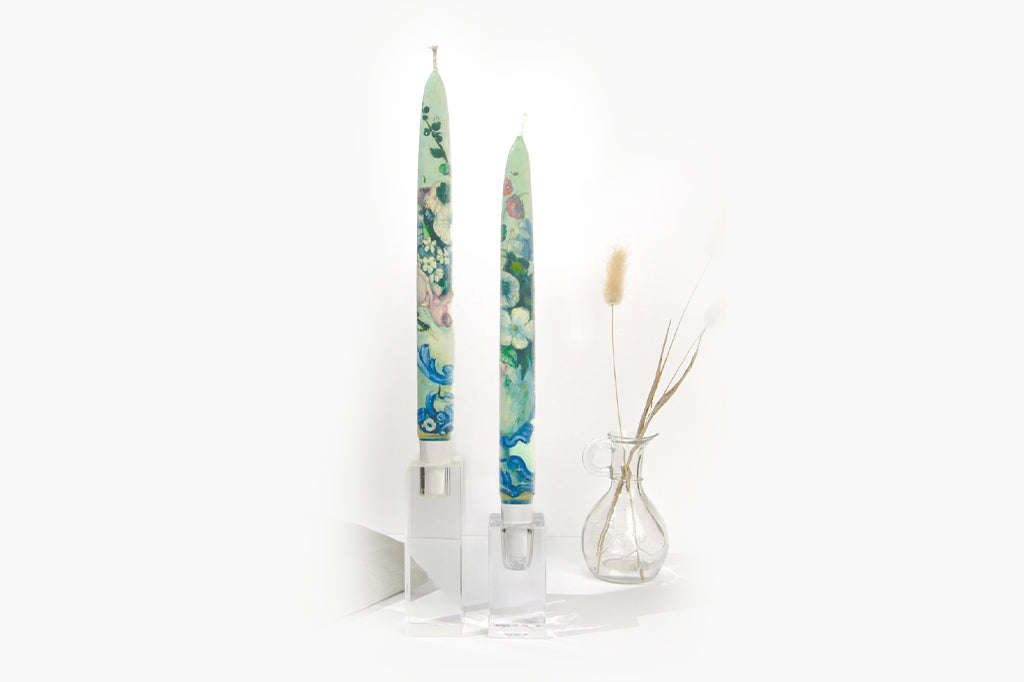 Tall floral-patterned candles in glass holders on a white background