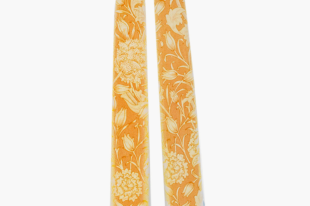 close-up view of flat, taper candles with decorative painted floral motif in orange