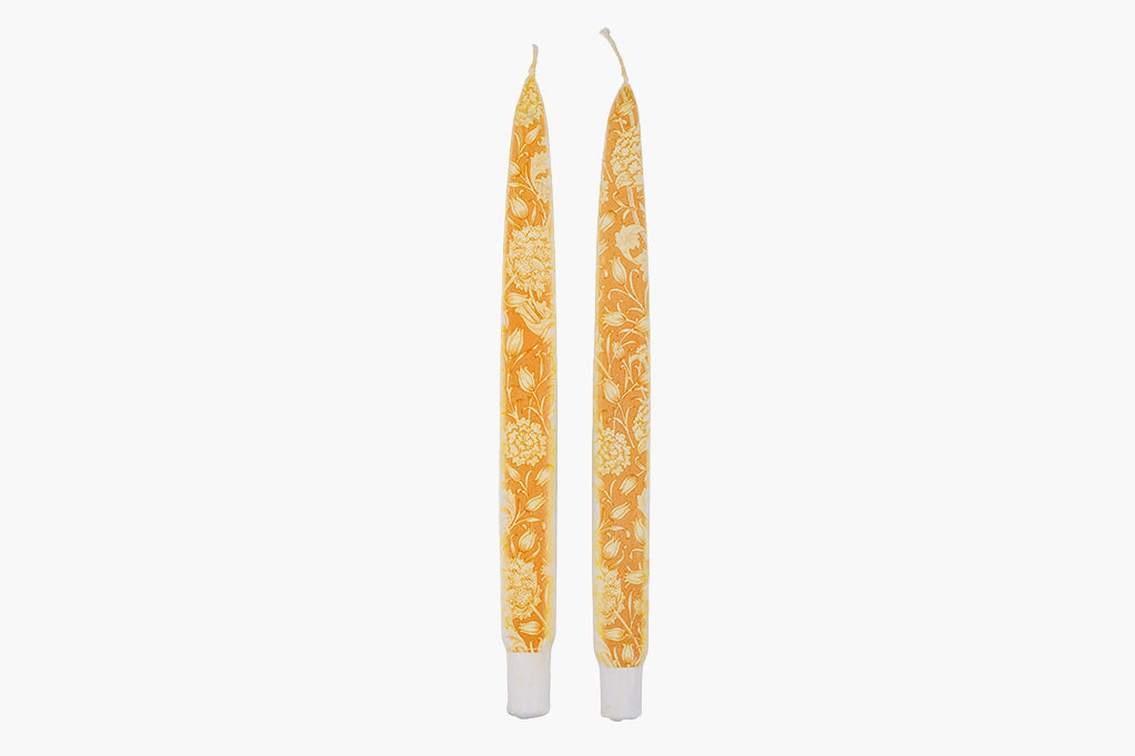 Two William Morris pattern in orange taper candles on white background