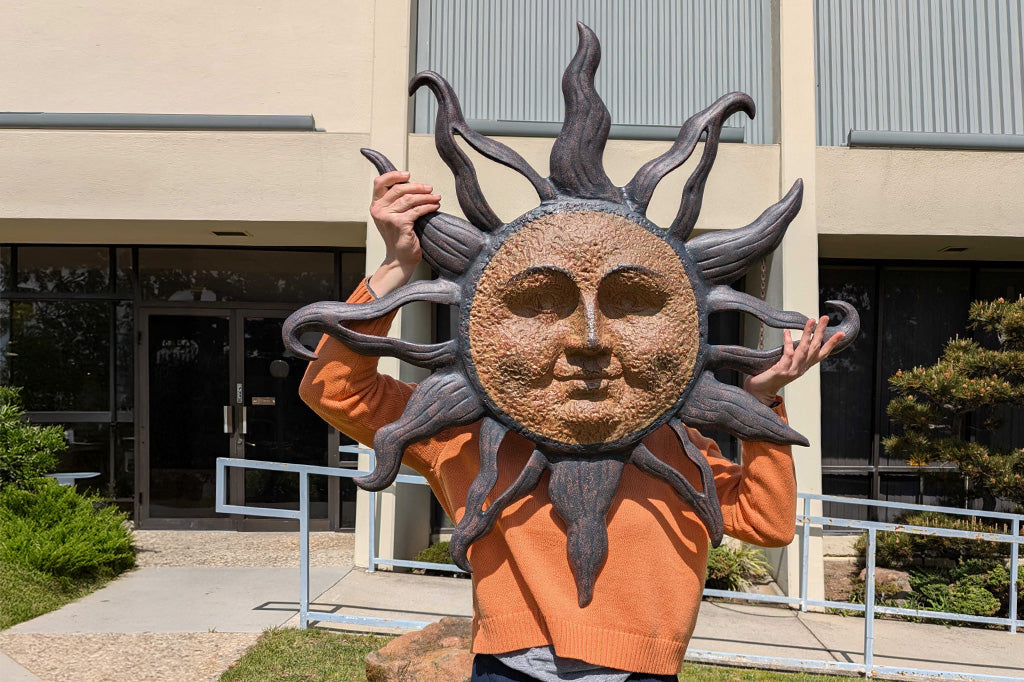 person holding large sun all plaque in front of their face at an office building
