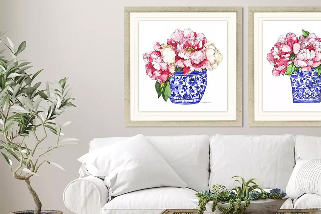 framed art of blue chinoiserie pot with pink peonies set on wall above couch