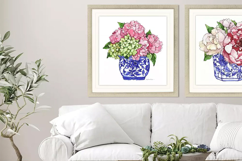 framed art print of hydrangea blossoms in a blue and white pottery vase, watercolor style print shown in room above couch