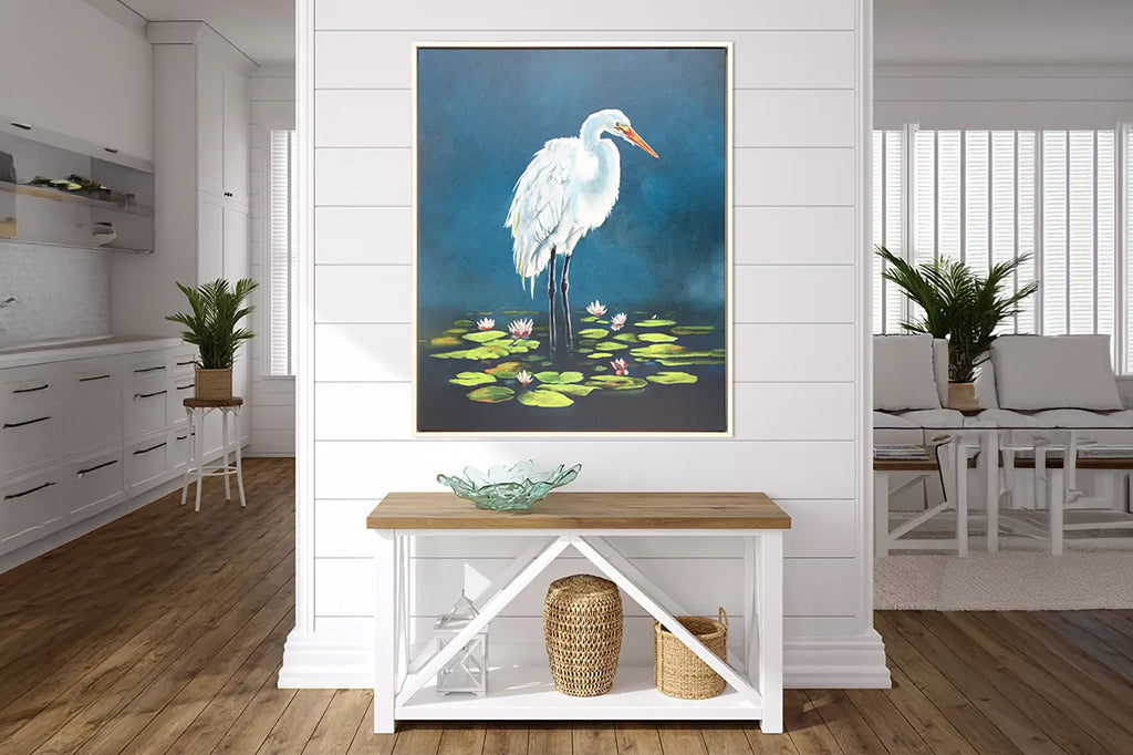 framed white egret standing in lily pond framed art, styled in beach home above a bench