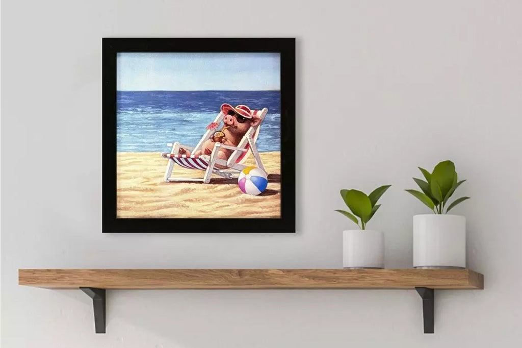 framed print of vacation piggy relaxing in a reclining chair on beach with shades and a coconut drink. Mounted on wall with black frame
