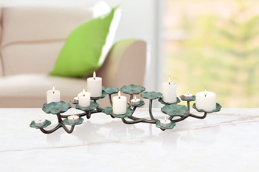 lily pad themed table candelabra holds a variety of candle sizes from pillar to tealight - holds up to 17 candles. shown on marble table in living room scene with window and couch in background