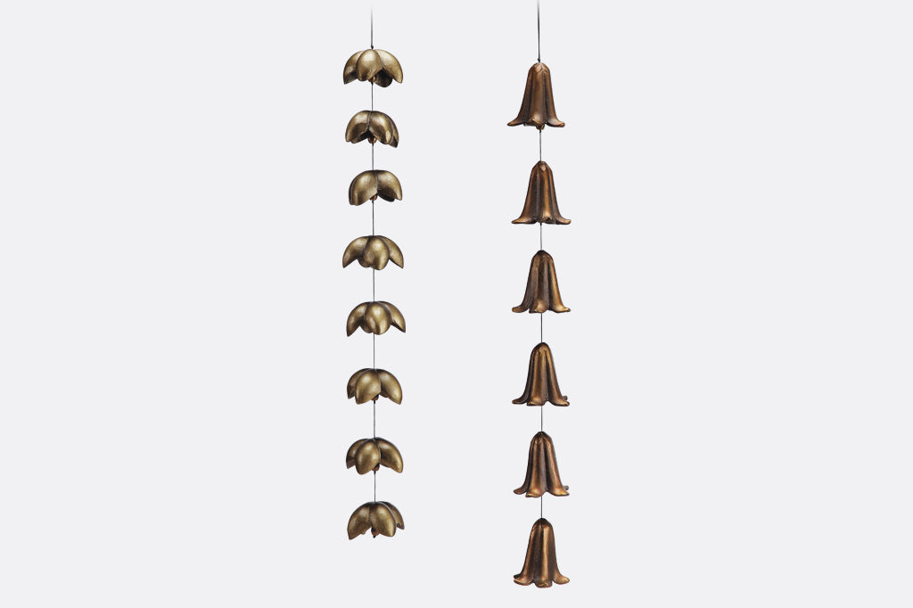 Decorative hanging metal bells with bronze bell-like shapes on a white background