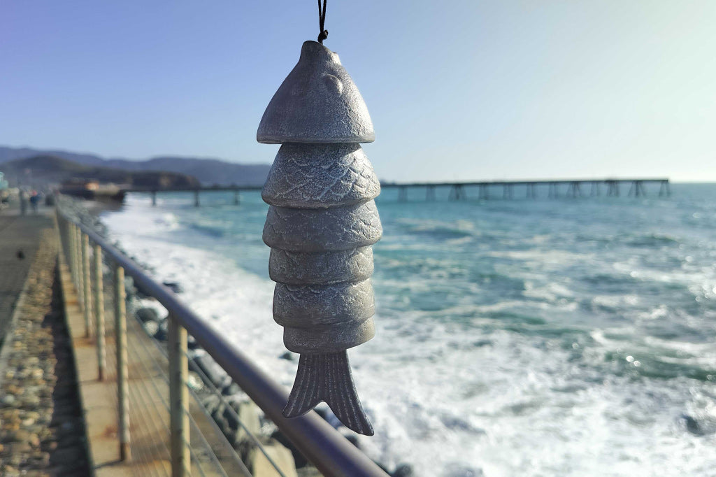 Fish Wind Art chime shown in front of ocean and pier in background