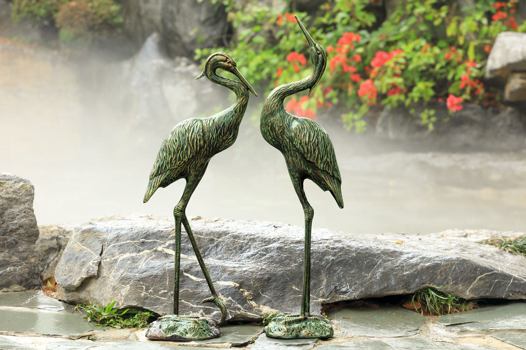 Garden Heron Pair sculpture in front of pond
