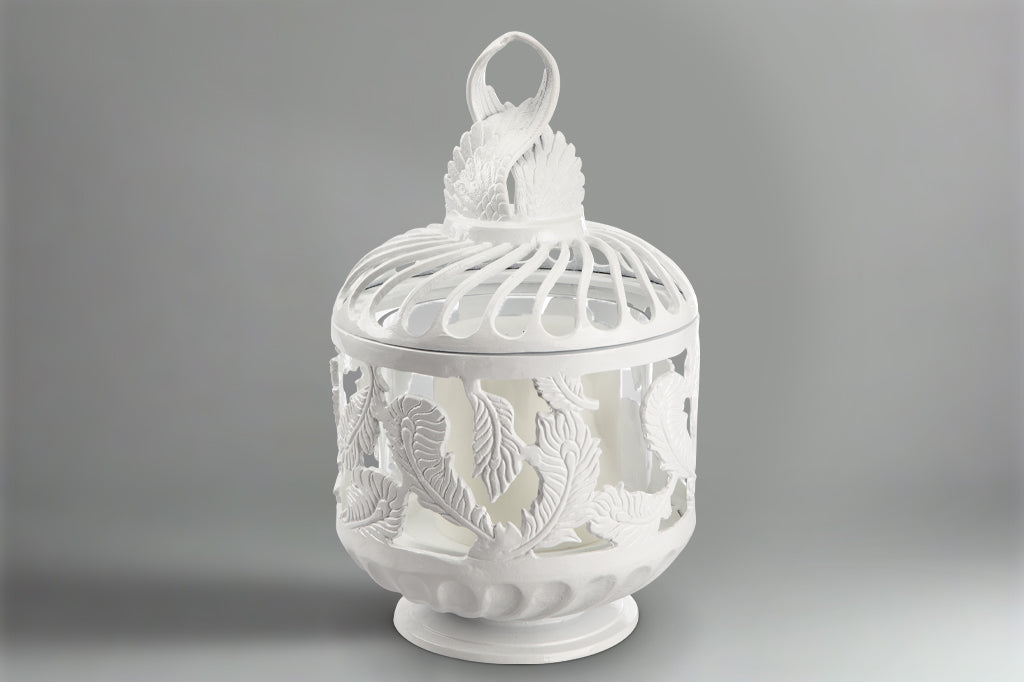 white cast metal swirling feather lantern shown with large pillar candle inside
#color_white