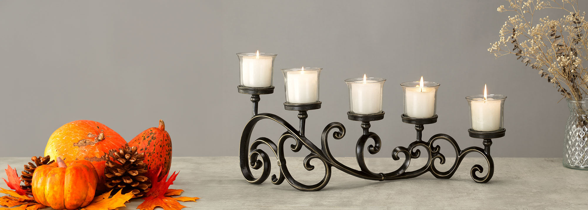 candelabra with 5 candles with glass holder on cast metal scrollwork holder, shown with autumn pumpkins on table