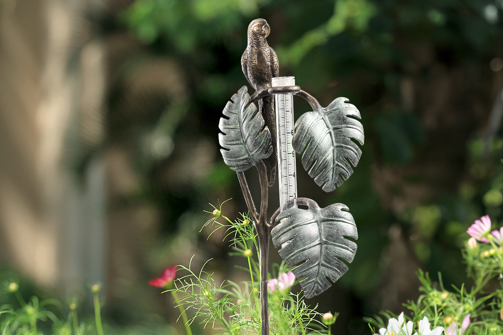 Sculptural rain catcher shaped like a Small parrot sitting on 3 tropical leaves