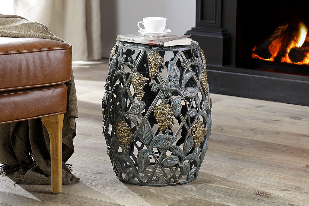 Cast metal garden stool of lattice design and vining blossoms shown in livingroom scene with fireplace in background