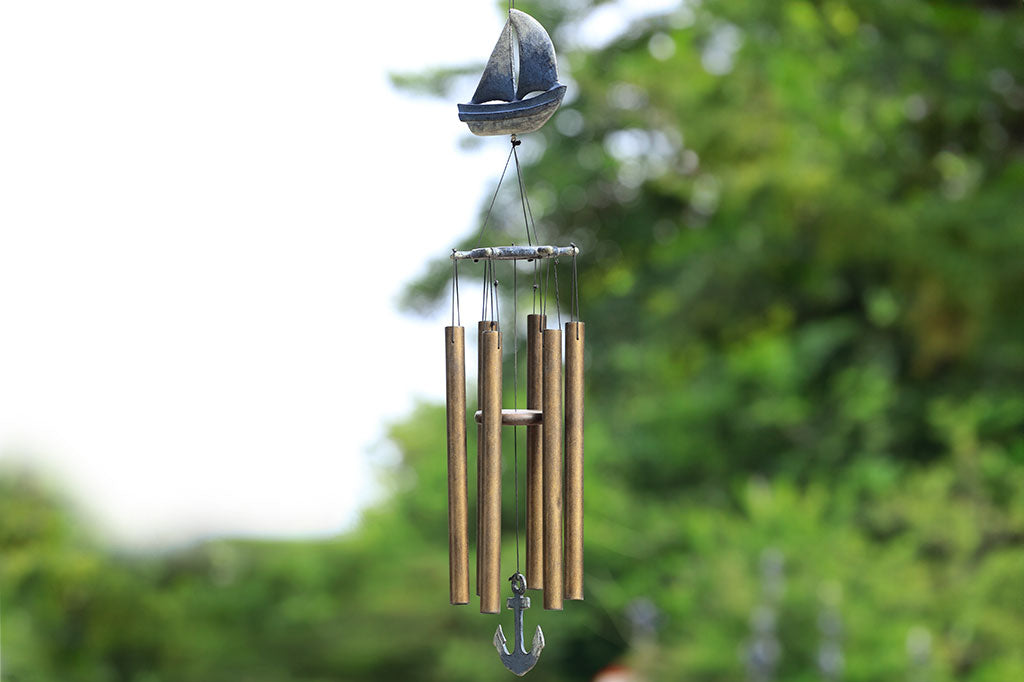 Wind chime with cast metal sail boat motif in zinc finish has 6 tube chimes and a pendant shaped like an anchor