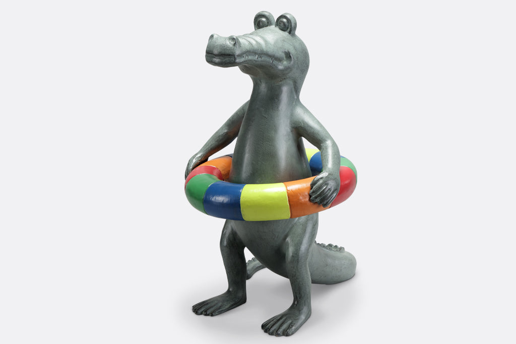 alligator with inner tube garden sculpture. Inner tube is bright colored stripped with red, yellow, orange, green and blue 