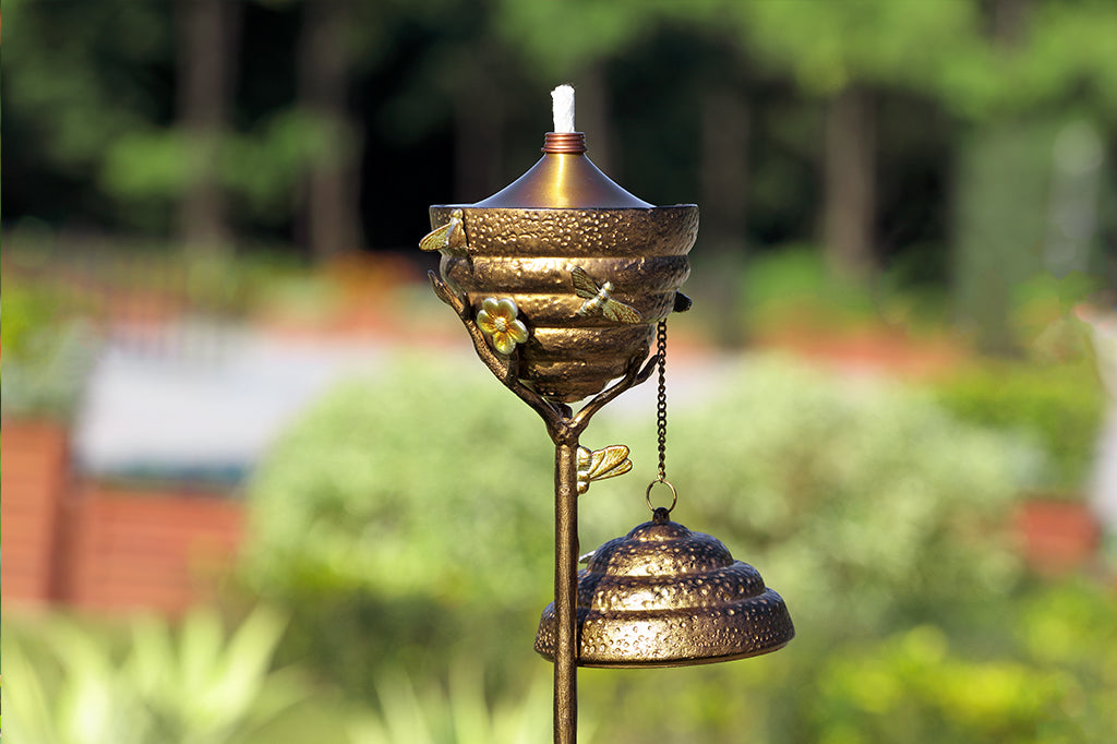 Metal Beehive oil torch with cap off placed in garden