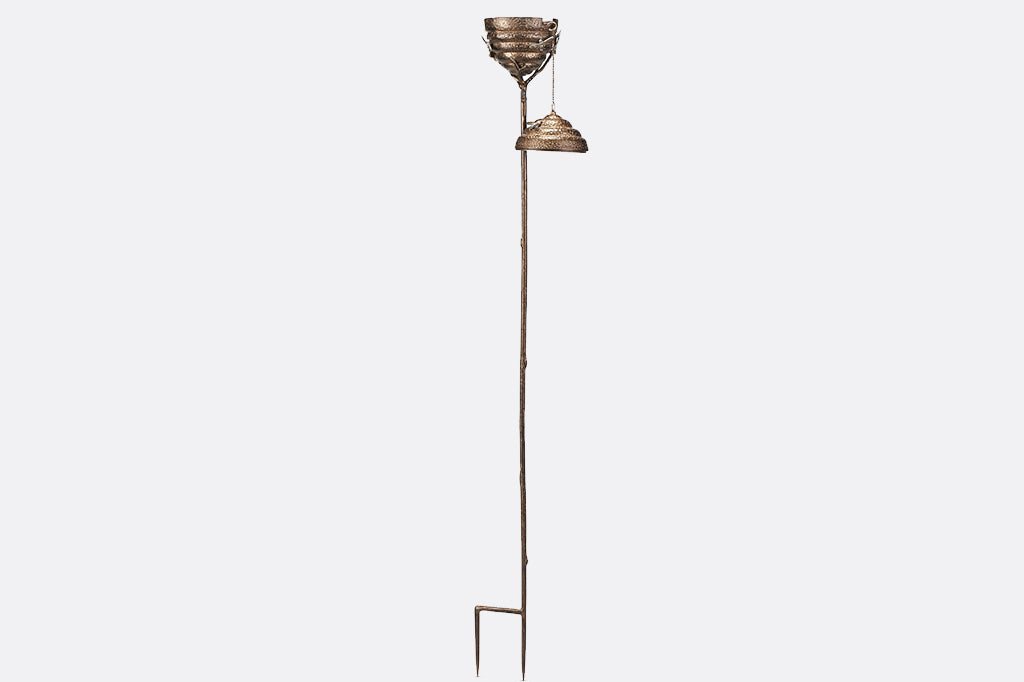 Metal Beehive oil torch with cap off, zoomed out showing stake