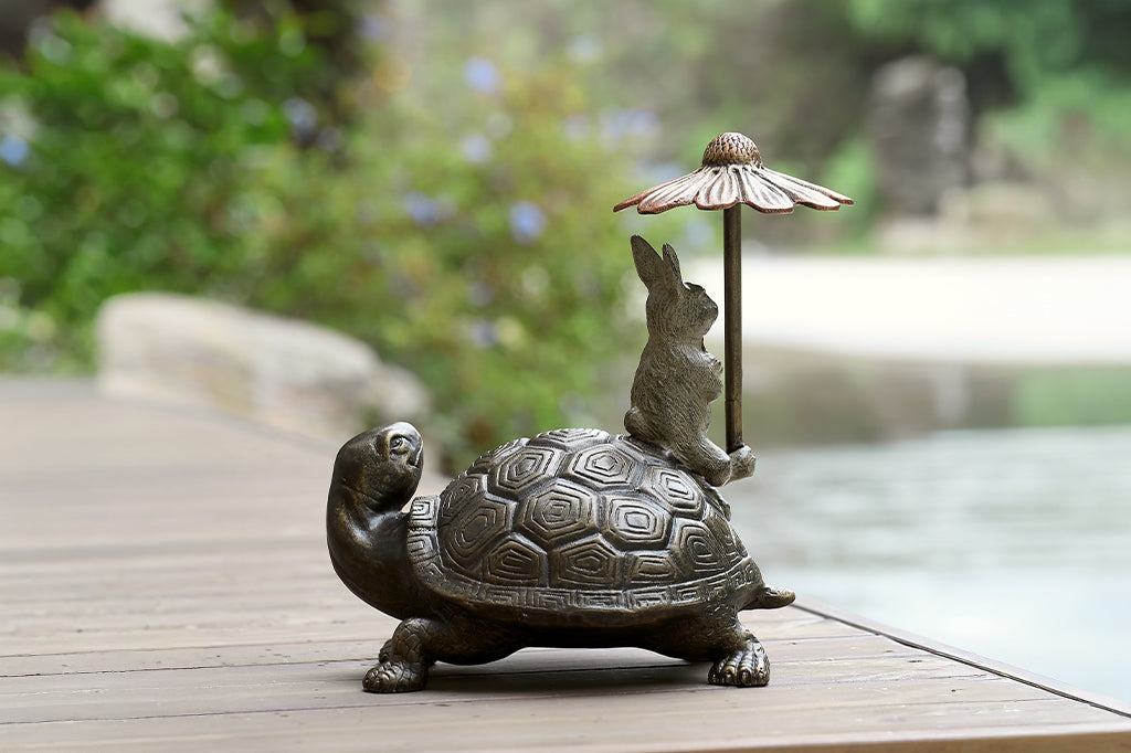 Bronze turtle and rabbit sculpture with an umbrella on a wooden surface. Hidden keybox underneath