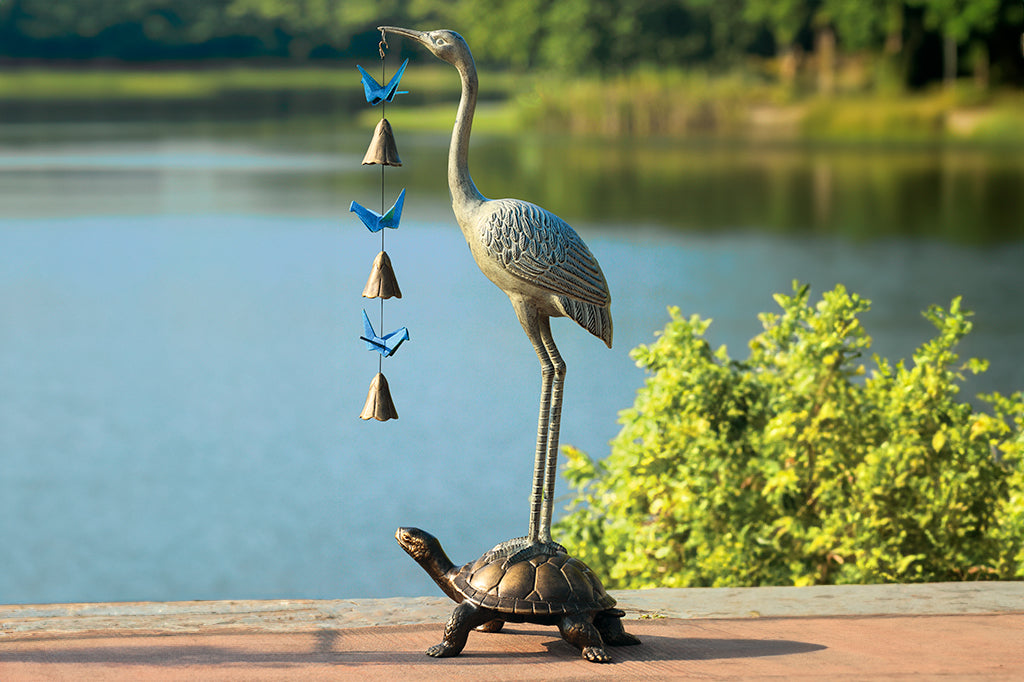 crane and turtle large sculpture; crane holding origami theme pendant by a lake