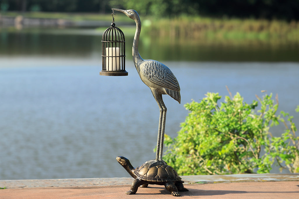 crane and turtle large sculpture; crane holding candle lantern by a lake