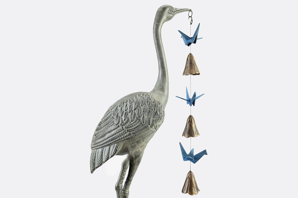 closeup view of crane holding origami metal wind art