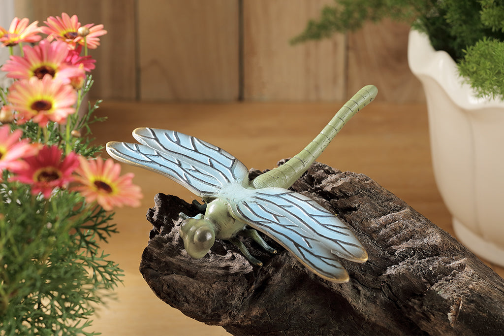 cast metal dragonfly garden sculpture shown by a floral arrangement, perched on decorative log