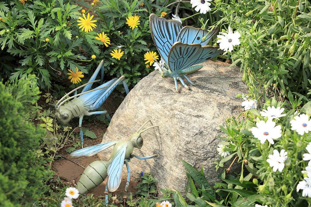 blue butterfly garden sculpture, blue grasshopper, blue wasp set in outdoor scene