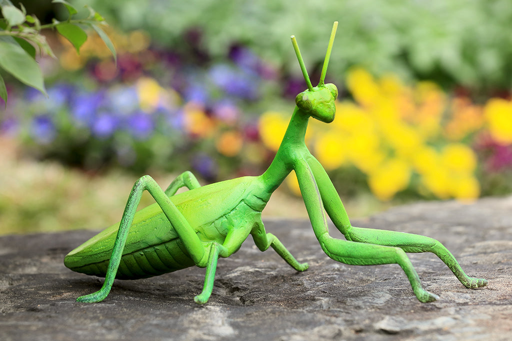cast metal bright green prayer mantis garden sculpture set on outdoor rock in garden