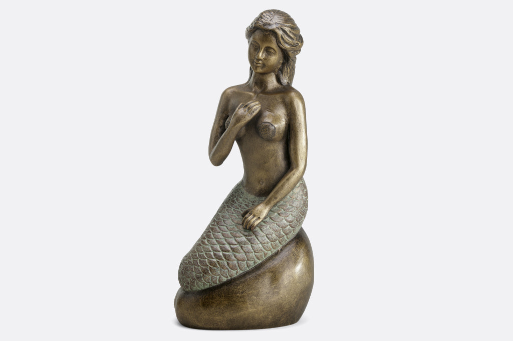 Metal mermaid seated on a rock garden sculpture