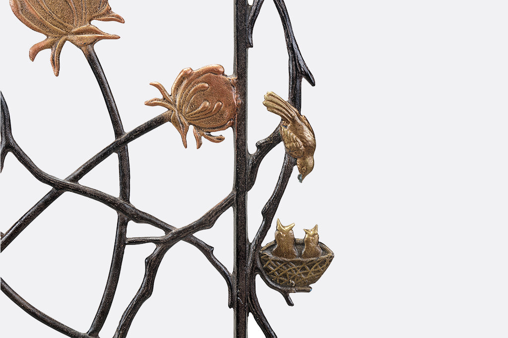 Detailed view of mother bird feeding two baby birds in nest on side of garden trellis