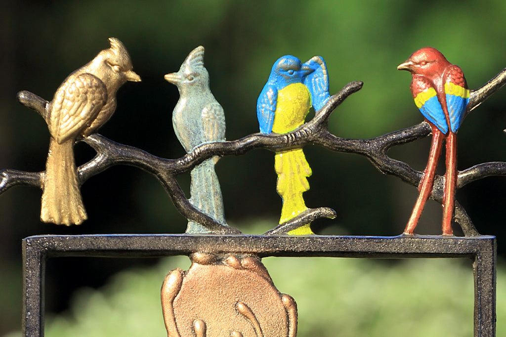 Metal garden trellis featuring quartet of birds, blue and red parrot, and flycatcher and cardinal
