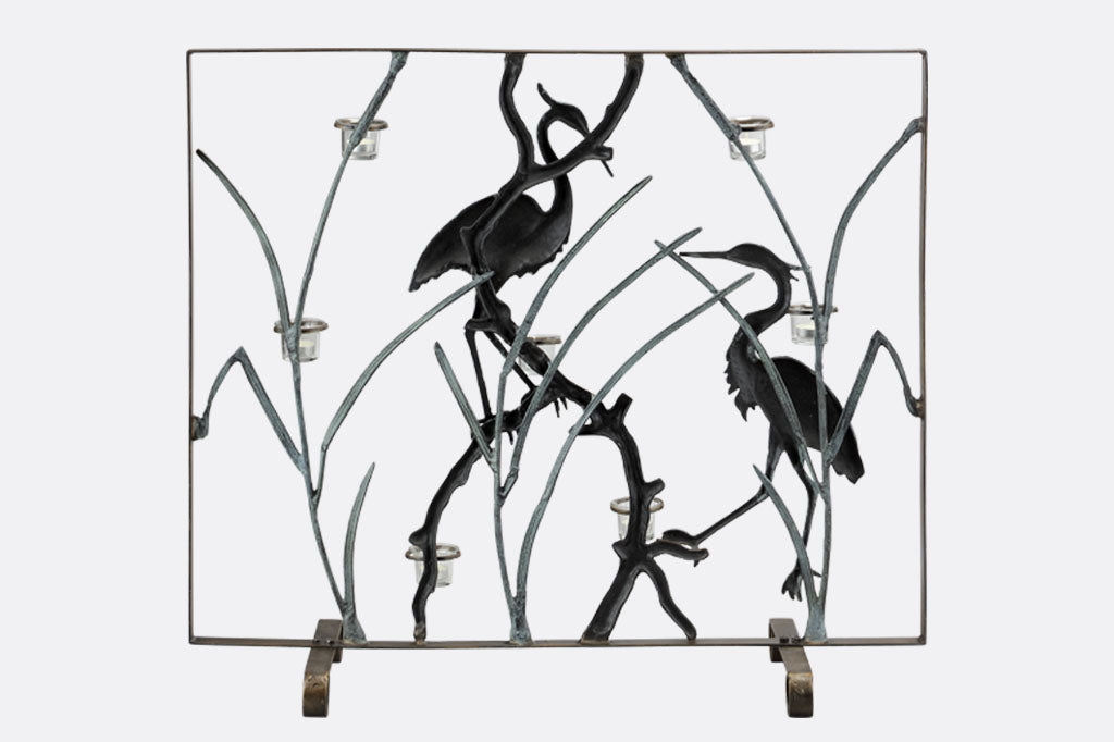 The back of a firescreen with Herons and branches holding tealight candles on a white background.