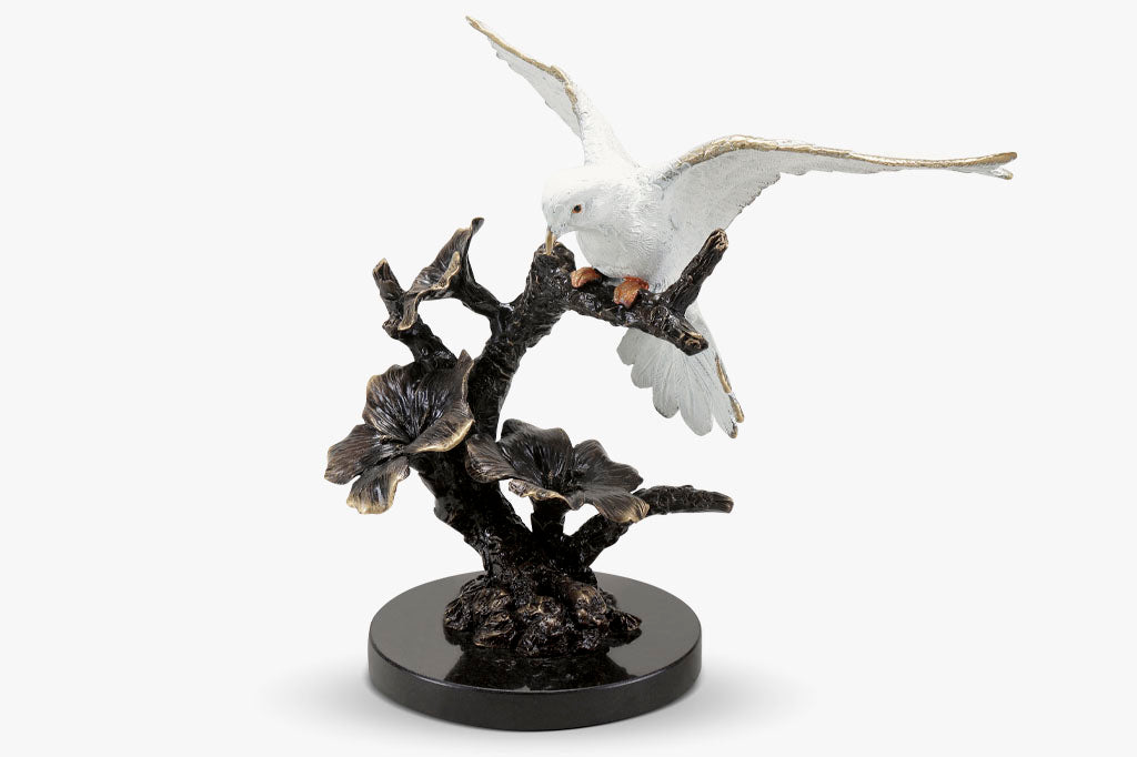 Brass sculpture of dove, with outstretched wings on a flowering branch