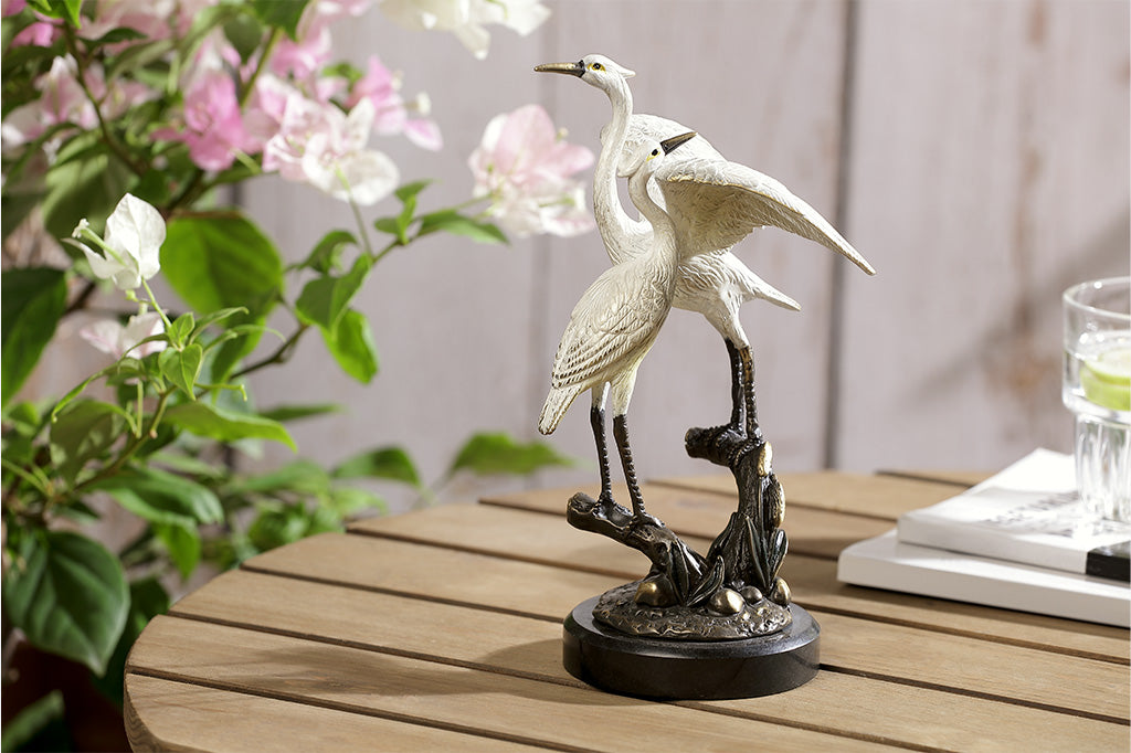 Statue of two cranes with a marble base placed on a table
