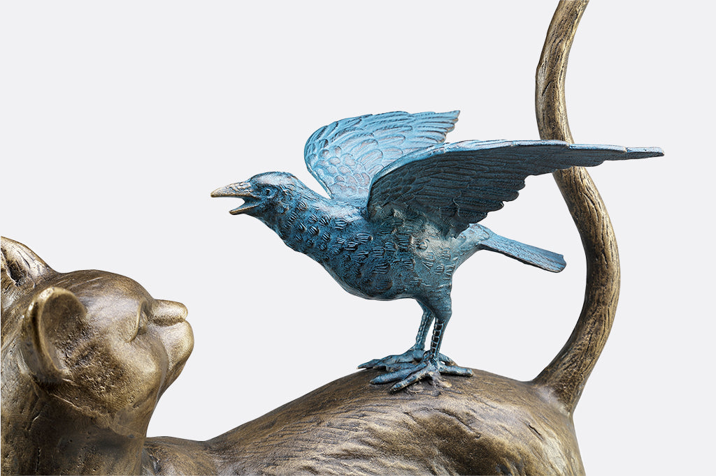 close-up detail of blue crow on cat's back garden sculpture